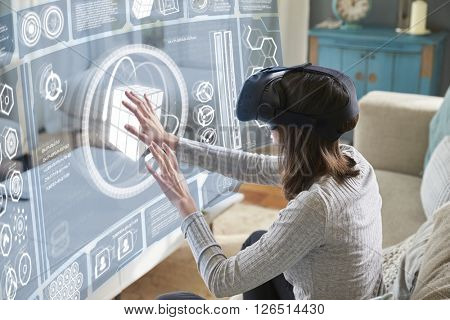 Woman Sits On Sofa At Home Wearing Virtual Reality Headset