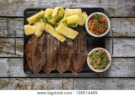 picanha portion and manioc fries. Wood background.