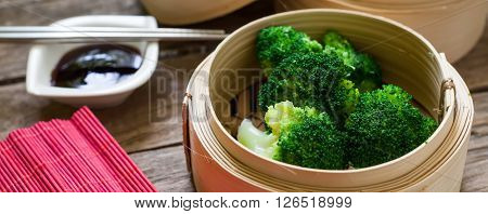 steamed fresh broccoli on bamboo pan with soya sauce for dip