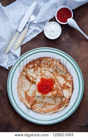 Blini with red caviar on a dark wooden background