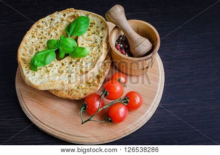 Italian dried bread Friselle on wooden board with tomatoes cherry, basil and peppercorns in wooden pounder. Italian food. Healthy vegetarian food.
