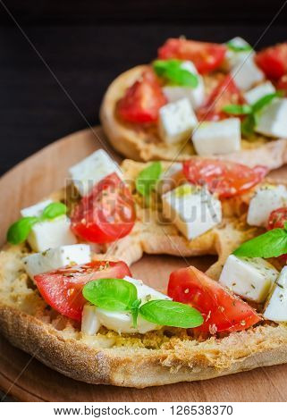 Italian starter friselle. Classical frisella tomato, cheese mozzarella and basil with oregano and olive oil. Dried bread called freselle on wooden board. Italian food. Healthy vegetarian food.