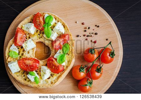Italian appetizer Friselle. Italian dried bread Friselle on wooden board with tomatoes cherry, basil and pepper. Italian food. Healthy vegetarian food. A quick and easy snack. Antipasti concept.