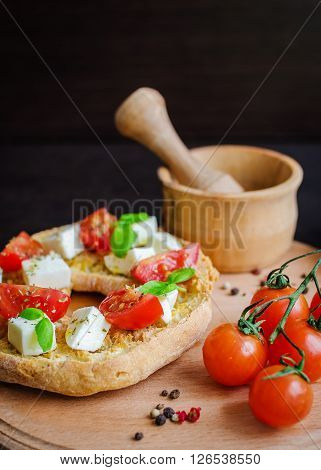 Italian appetizer Friselle. Italian dried bread Friselle on wooden board with tomatoes cherry, basil and peppercorns. Italian food. Healthy vegetarian food. Antipasti concept. Selective focus.