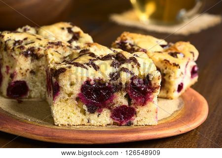 Cherry blondie or blond brownie cake baked with white and dark chocolate pieces photographed with natural light (Selective Focus Focus on the front of the first cake piece)
