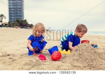 little boy and girl play with sand on beach