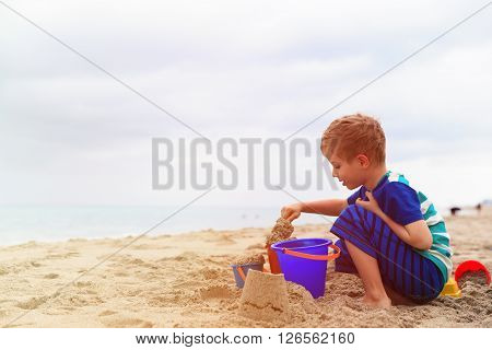 cute little boy play with sand on summer beach