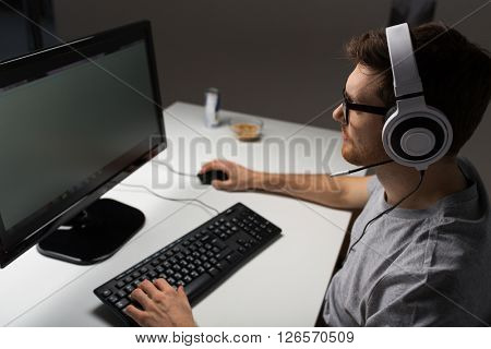 technology, gaming, entertainment, let's play and people concept - close up of young man in headset and glasses with pc computer playing game at home and streaming playthrough or walkthrough video
