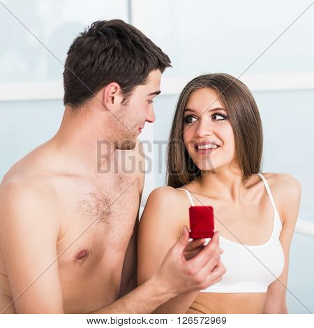 Man makes a proposal to his girlfriend in the bed at home