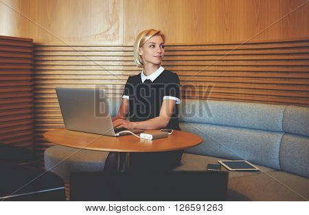 Female entrepreneur is looking awaywhile is waiting file download of confidential information about her enterprise on laptop computer.Woman lawyer is using net-book for prepare to meeting with client