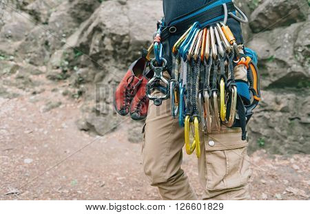 Unrecognizable woman rock climber wearing in safety harness with quickdraws and climbing equipment outdoor