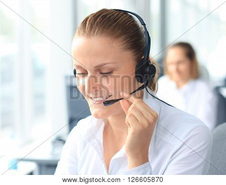 Beautiful young female call center operator with headset in office