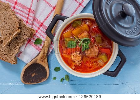 Goulash In A Black Cocotte With Marjoram On Blue Wood