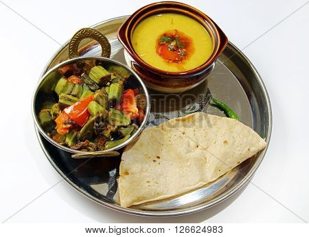 An Indian platter of Bhindi masala Chapati arhar lentil daal isolated on white background.