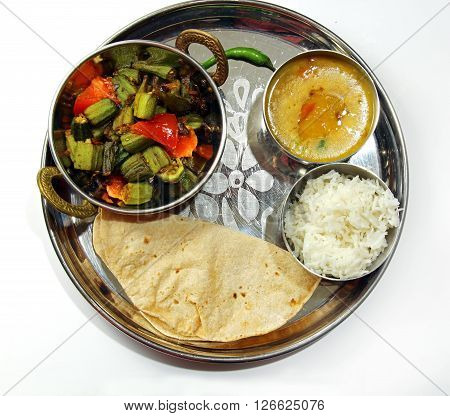 An Indian platter of Bhindi masala Chapati arhar lentil daal isolated on white background.