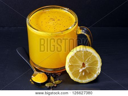 Spicy healthy Haldi or Turmeric lemon and pepper antioxidant drink with lemon on a moody background.