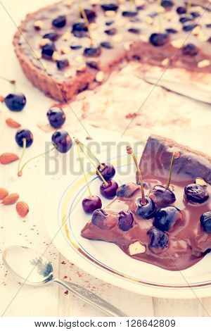 Piece of chocolate tart with cherries on the plate.Selective focus on the piece in plate