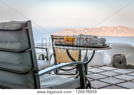 Breakfast table with juice and meal on balcony at Santorini island