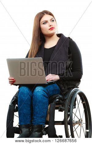 Real people disability and handicap concept. Teen girl unrecognizable person sitting on wheelchair using laptop computer networking studio shot on white