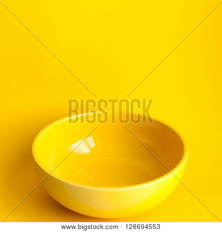 New clean yellow bowl on yellow background. Frontal view