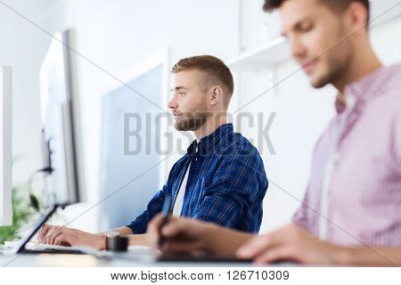 business, technology, education and people concept - young creative man or designer with computer at office