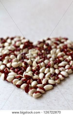 White kidney beans with red spots on the marble sutface close-up. vertical
