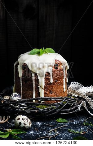 Easter cake on dark background with quail eggs in wreath of twigs with leaves