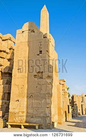 LUXOR EGYPT - OCTOBER 7 2014: The top of the Hatshepsut Obelisk is seen behind the ruined wall of the  on October 7 in Luxor.