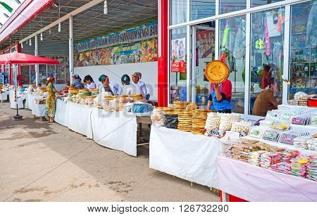 PUNGAN UZBEKISTAN - MAY 6 2015: The rustic food market with the wide range of lochira (traditional flat bread) sundried cheese balls (kurt) and sweets on May 6 in Pungan.
