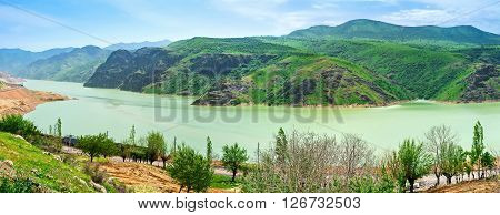 The bright green slopes of Qurama mountain range and the Achangaran reservoir on the foreground Uzbekistan.