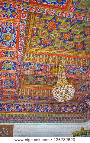 KOKAND UZBEKISTAN - MAY 6 2015: The ceiling in room of Khudayar Khan Palace with colorful floral and stellar patterns on the carved wood on May 6 in Kokand.