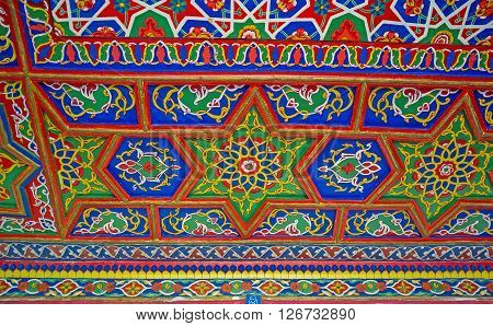 KOKAND UZBEKISTAN - MAY 6 2015: The colorful wooden ceiling in Khudayar Khan Palace decorated with the stellar and floral patterns in eastern style on May 6 in Kokand.