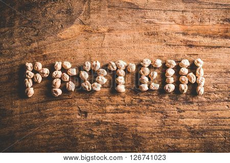 protein written with chickpeas on wood background