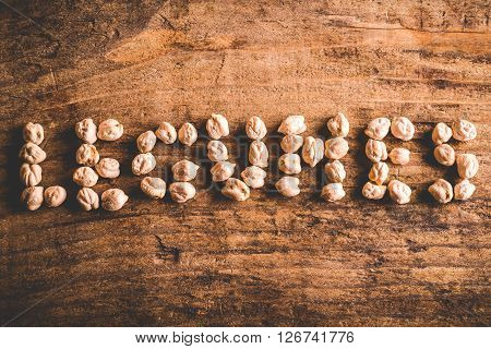 legumes written with chickpeas on wood background