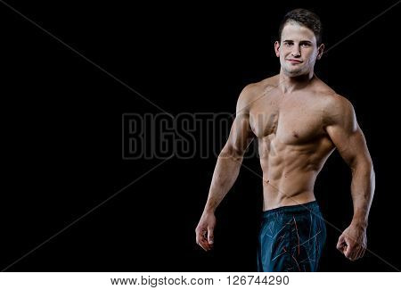Studio shot on black background. Showing six packs of abs.