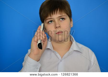 Teen boy talking by a radiotelephony on a blue background