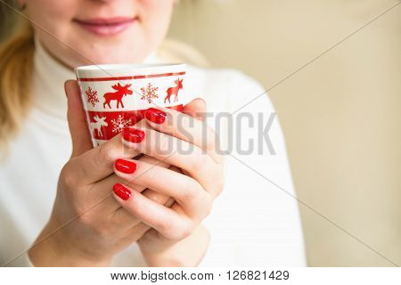 Close up of hands with a cup. Protect your health. Drink herbal tea. Woman holding a red cup of hot drink. Drink hot tea or coffee in the morning cool. Traditional autumn or winter warming drink.