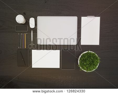 Topview of dark wooden desktop with closed laptop small plant and other office tools. Mock up 3D Rendering