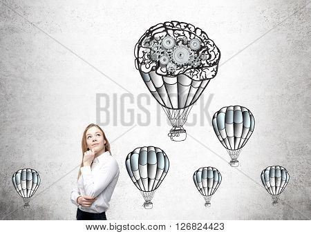 Businesswoman with airballoons and gears skecth on concrete wall