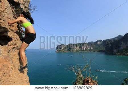 young woman rock climber climbing at seaside mountain rock