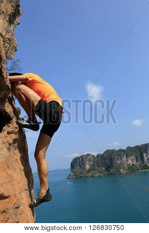 young woman rock climber climbing at seaside mountain rock