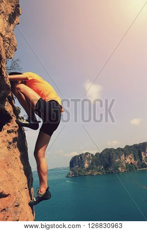 young woman rock climber climbing at seaside mountain rock