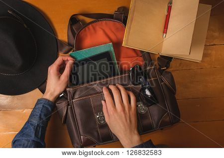 Preparing vintage bag to travel. Men's hands, vintage hat, bag, diary and sungalsses