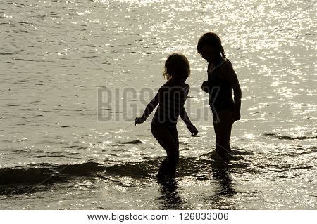 Children playing in sunlit sea in summer