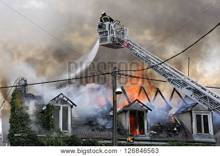 Fire fighter fighting a burning house with water