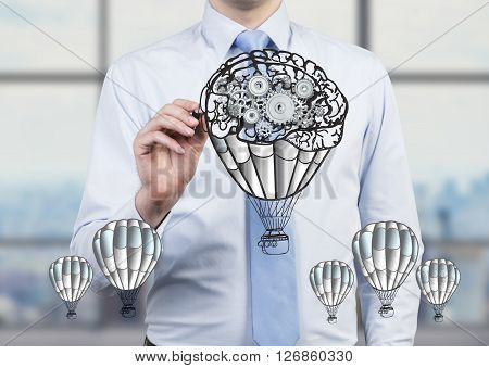 Businessman drawing abstract airballoon and gear sketch