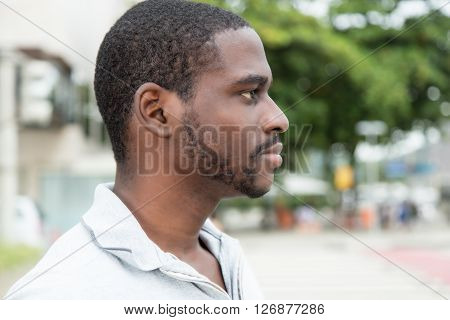 African man with beard looking sideways outdoor in the city