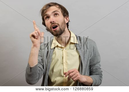 Young man having a good idea against grey wall background