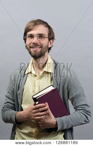 Young man Standing Smiling Holding books  on Isolate grey Background