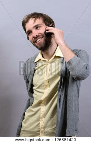 Man talking on the phone.  against grey wall background